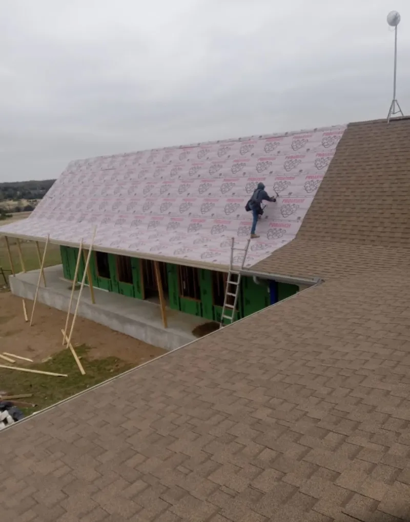 Worker preparing underlayment for a metal roof installation in Fort Dodge